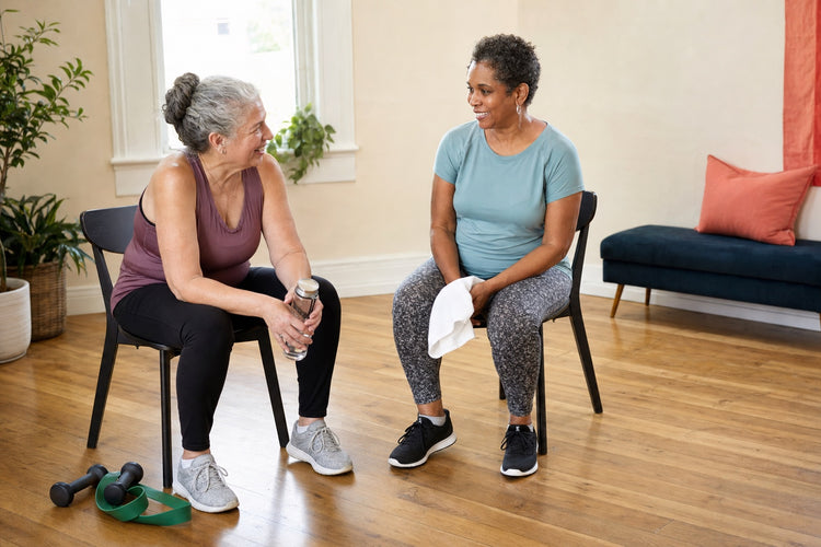 Two women taking a break together after a beginner strength session.